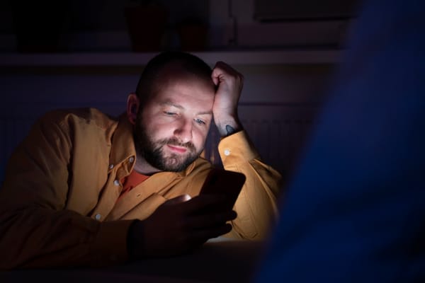 Worried parent looking at their phone in the dark.