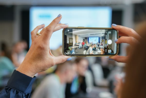 A close up of a woman taking a photo using her phone. We see her phone screen and the image she is taking. 